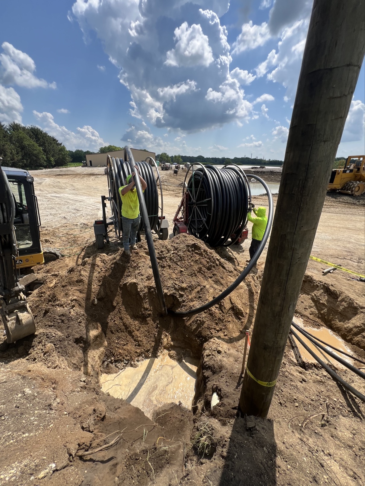 Crew pulling HDPE conduit from reels on job site